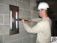 Attempting to straighten a bowed foundation wall by straightening a wall anchor system in a Winkler home.