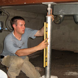 A contractor in Lockport installing a crawl space jack post.