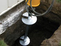 Installing a helical pier system in the earth around a foundation in Selkirk
