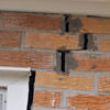 A brick wall displaying stair-step cracks and messy tuckpointing on a Selkirk home