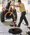 Digging a hole in the garage floor to make room for a wall anchor installation in Gimli, Manitoba